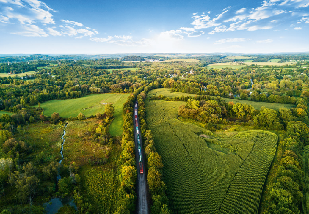 Güterzug unterwegs auf der Schiene, in grüner Landschaft.