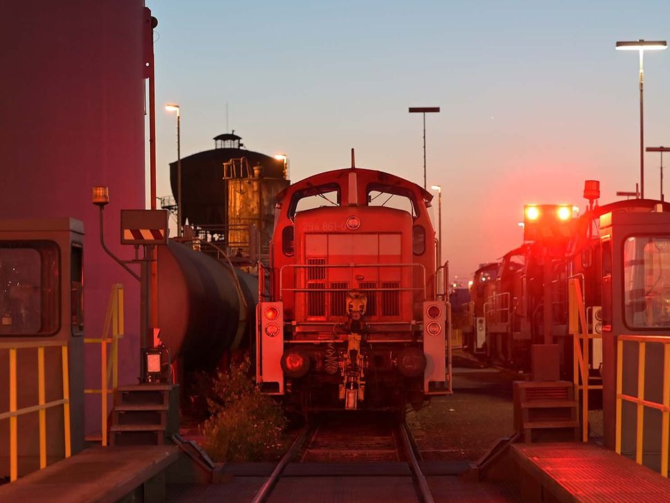 Eine Rangierlok steht auf einem Rangierbahnhof im Dämmerlicht.