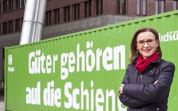 Dr. Sigrid Nikutta steht vor einem grünen Container mit der Aufschrift Güter gehören auf die Schiene.