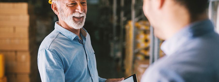 Two warehouse specialists shake hands and operate link2rail on a tablet