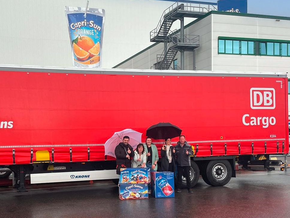 Mehrere Personen stehen vor einem Anhänger von DB Cargo.