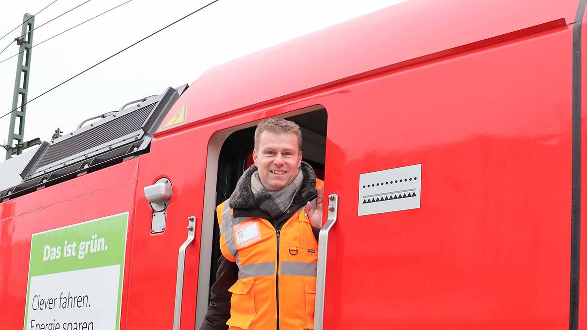 Ein Mann guckt aus der Tür einer Lokomotive.