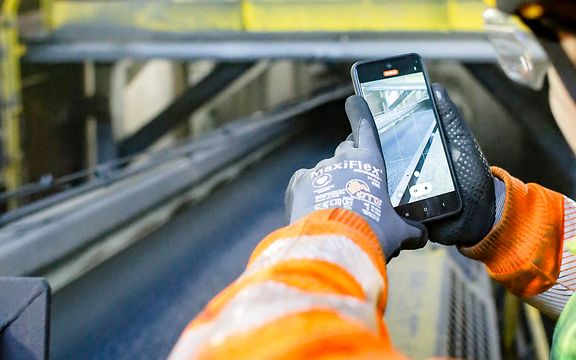 Employee films the unloader of sponge iron with his smartphone.