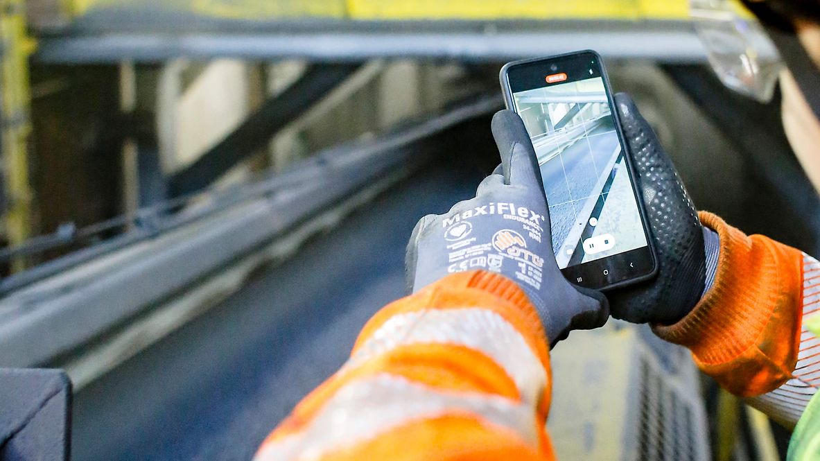 Employee films the unloader of sponge iron with his smartphone.