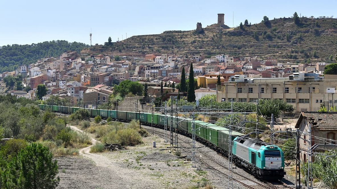Ein Zug fährt durch eine mediterrane Landschaft.
