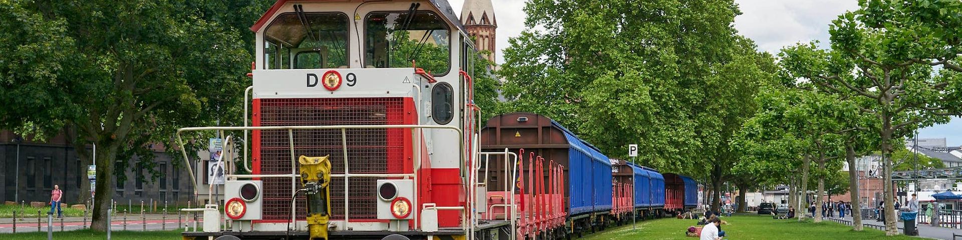 Eine Lok zieht Güterwagen am Frankfurter Mainufer.