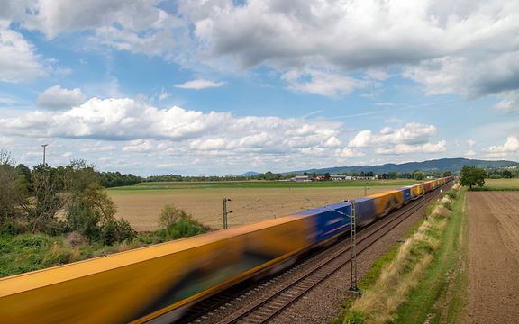 Ein mit mehreren Containern beladener Güterzug von DB Cargo fährt über eine Brücke.