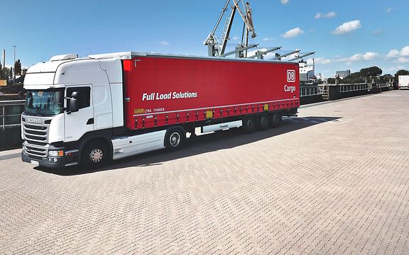 Five red DB Cargo FLS trailers on a freight train. A trailer is being transshipped.