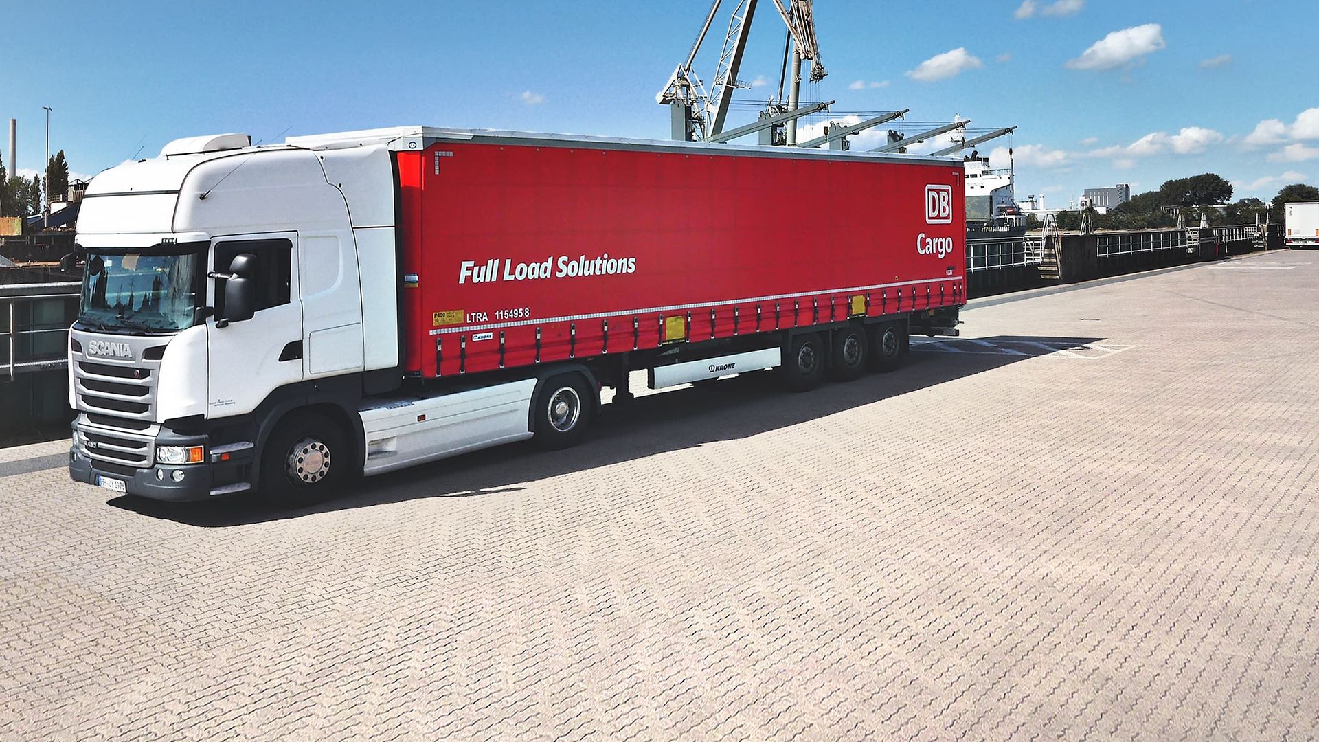 Five red DB Cargo FLS trailers on a freight train. A trailer is being transshipped.