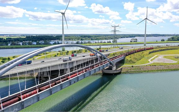 Railroad bridge with wind turbines in the background.