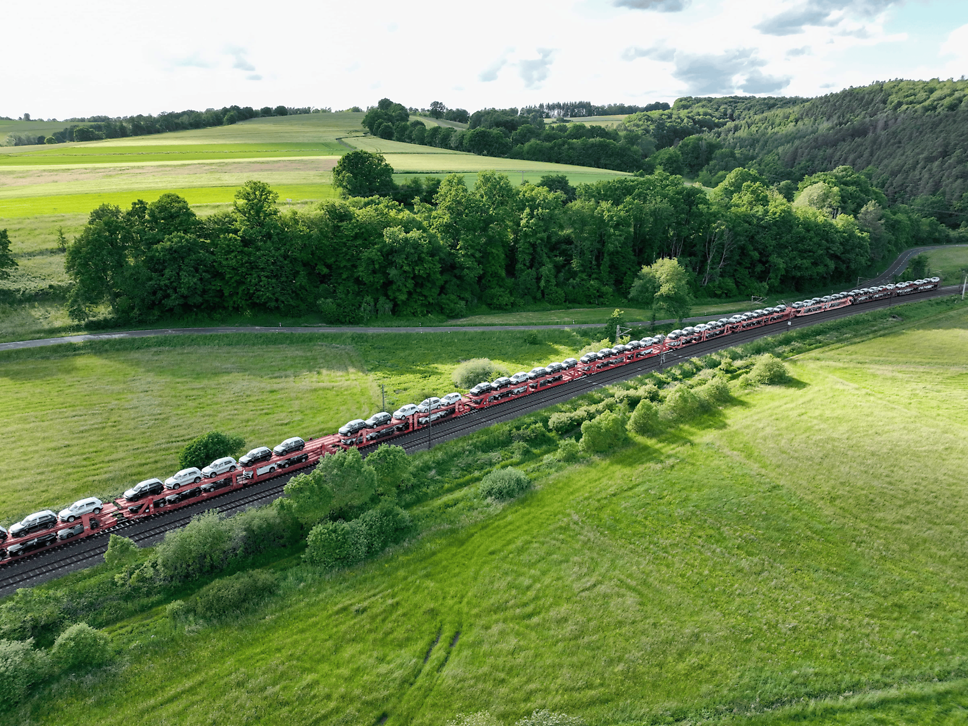 Train with car carrier wagons travelling through green countryside