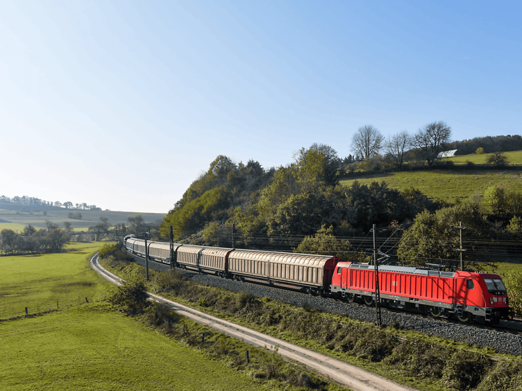 DB Cargo's red locomotive running through green countryside with sliding-wall wagons