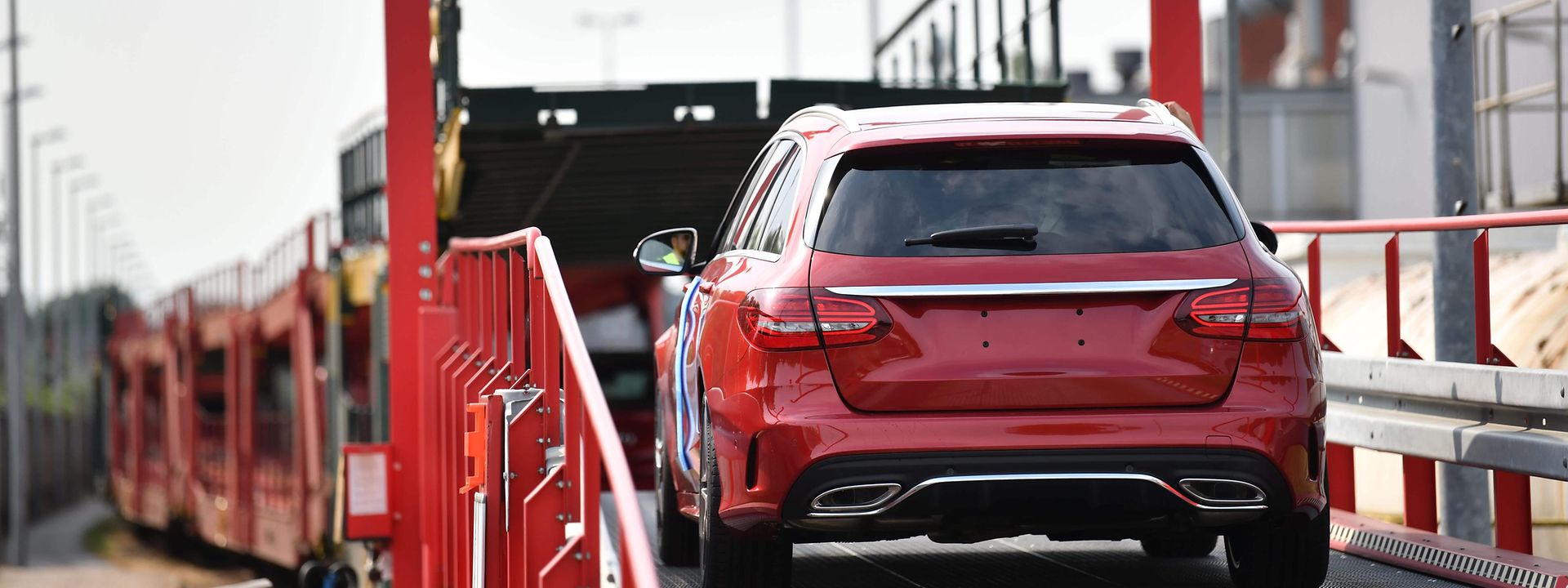 Red car drives onto double-decker wagon