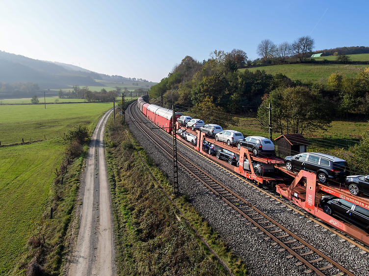 Freight train with car carrier wagons travelling through green countryside
