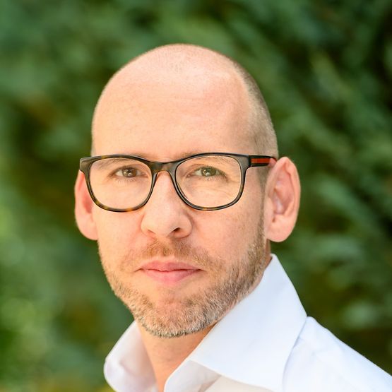 Ein Mann mit Brille der direkt in die Kamera schaut. 