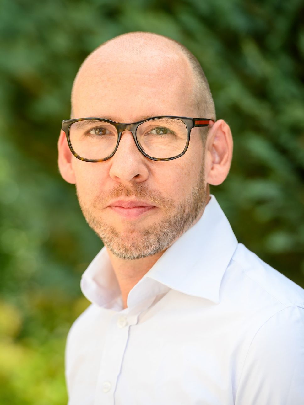 Ein Mann mit Brille der direkt in die Kamera schaut. 