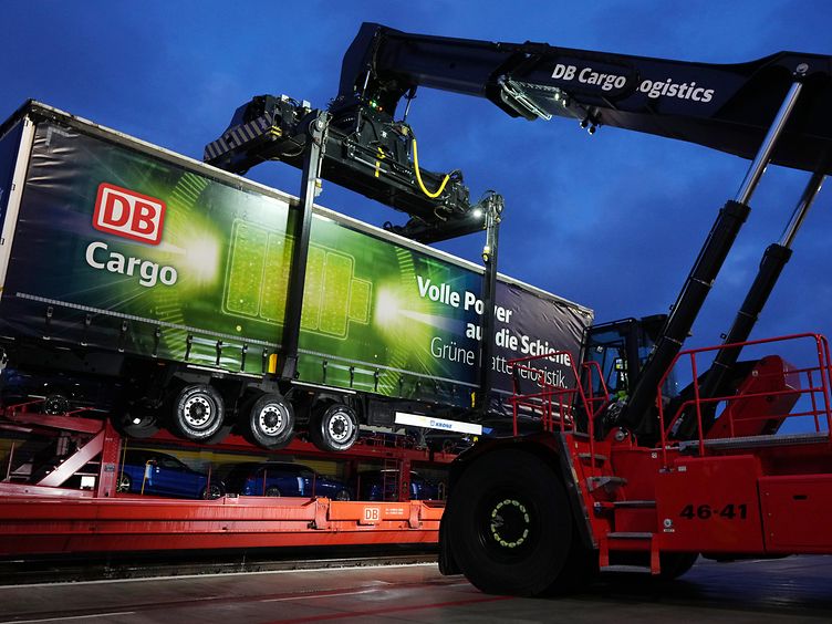 Intermodal rail transport with vehicle parts: A trailer is loaded onto the rail using a crane.