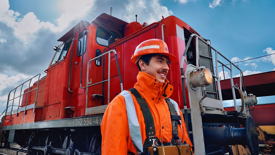 Ein Lokrangierführer in Warnweste und mit Schutzhelm läuft vor einem Triebwagen des Güterverkehrs entlang