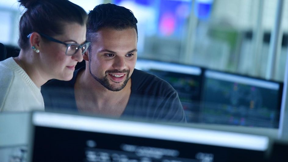 Zwei Mitarbeiter sitzen vor einem Bildschirm