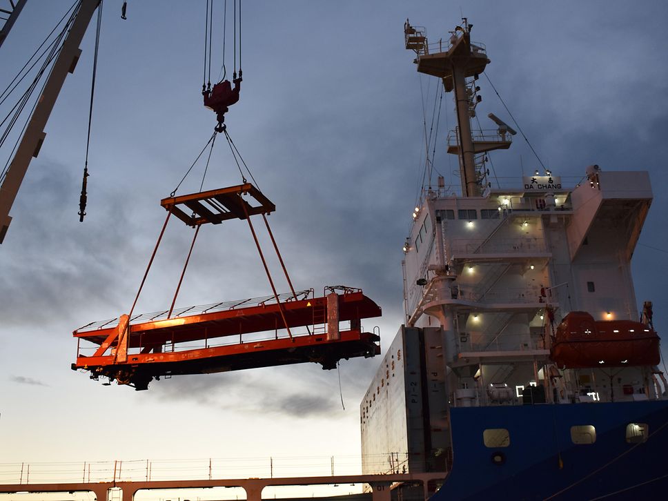 A car carrier wagon is lifted from a ship by crane.