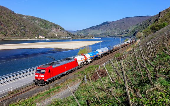 Eine Güterzug von DB Cargo auf der Rheinstrecke, im Hintergrund sieht man den Rhein mit Niedrigwasser.