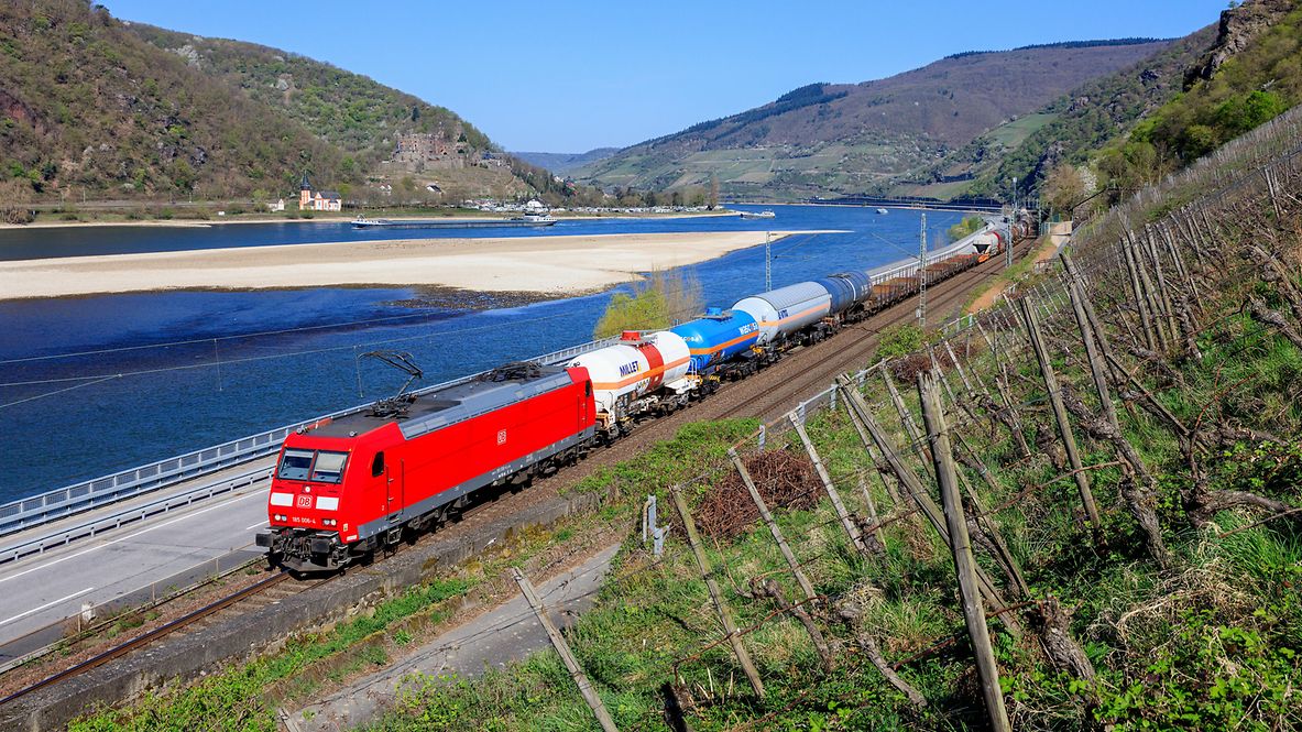 Eine Güterzug von DB Cargo auf der Rheinstrecke, im Hintergrund sieht man den Rhein mit Niedrigwasser.