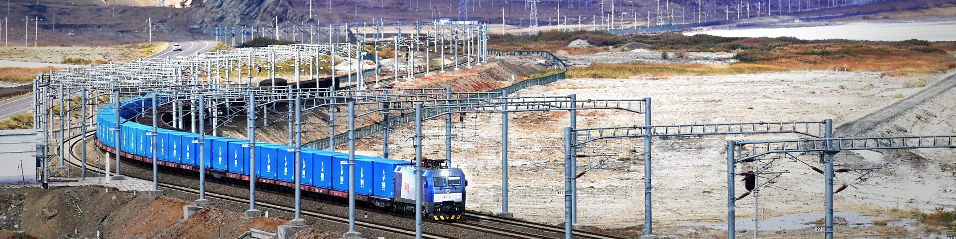 Blauer Güterzug auf dem Weg durch ein kahles asiatisches Gebirge