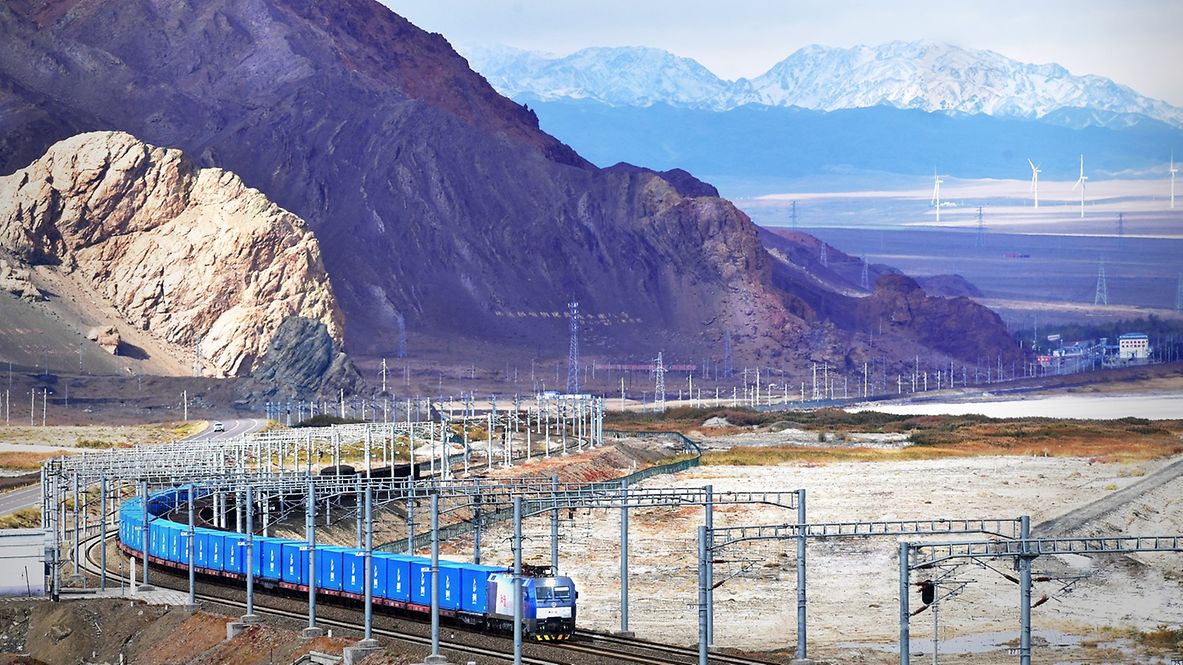Blauer Güterzug auf dem Weg durch ein kahles asiatisches Gebirge