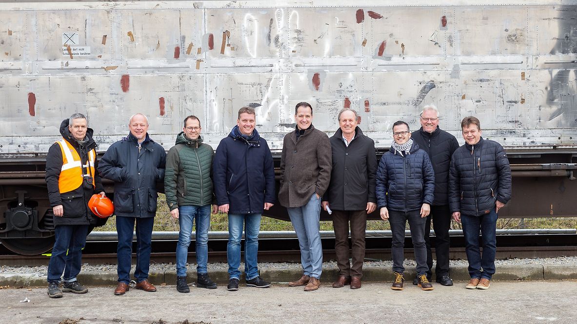 Das Team von DB Cargo Logistics und Mitarbeiter von Binderholz und Bürgermeister Schwarz vor einem beladenen Waggon.