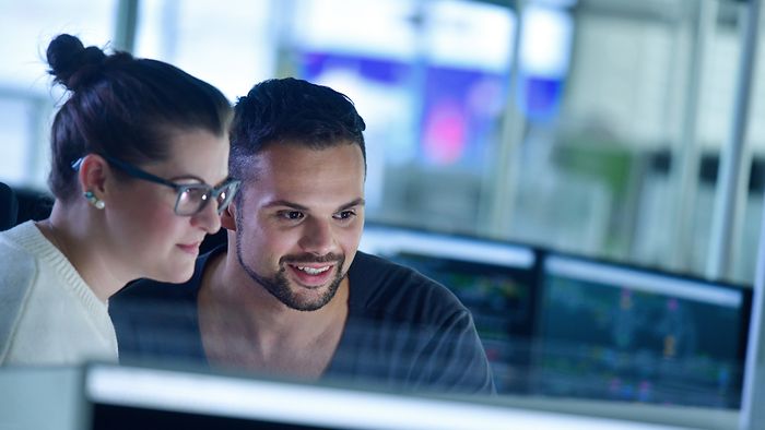 Two employees watching a screen