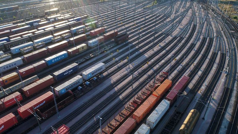 Großer Güterbahnhof mit verschiedenfarbigen Waggons im Abendlicht