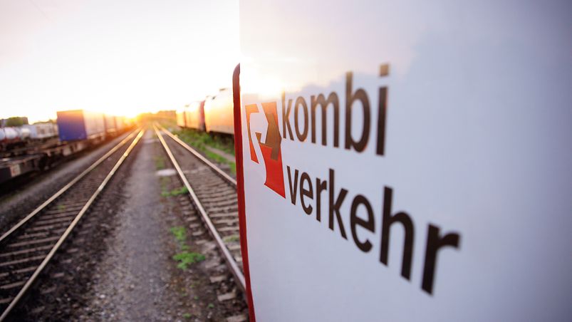 Eine Kombiverkehr-Lok steht bei Sonnenuntergang im Gleisbett.